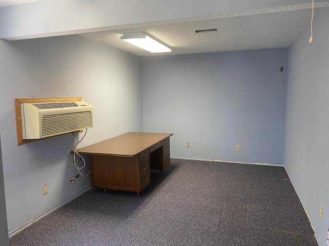 unfurnished office with an AC wall unit, a textured ceiling, and dark colored carpet