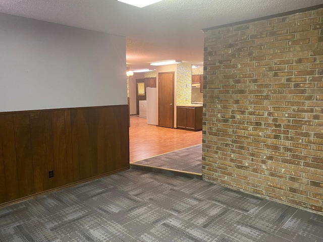 unfurnished room featuring wooden walls and a textured ceiling