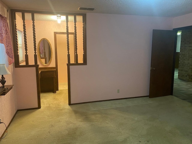 spare room featuring light carpet and a textured ceiling