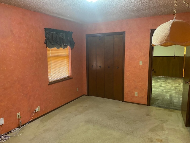 unfurnished bedroom with light colored carpet, a closet, and a textured ceiling