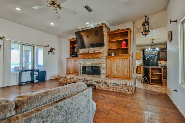 living room with a brick fireplace, wood-type flooring, and ceiling fan