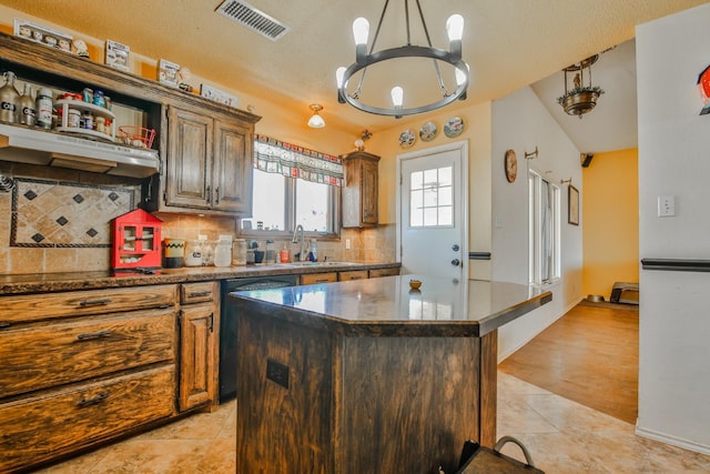 kitchen featuring sink, a center island, light tile patterned floors, black dishwasher, and backsplash