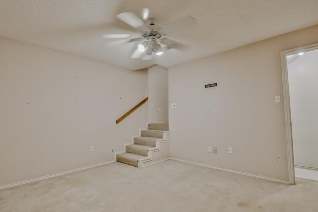 basement with light carpet, ceiling fan, and a textured ceiling