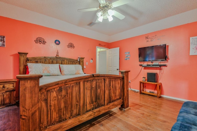 bedroom featuring ceiling fan, hardwood / wood-style flooring, and a textured ceiling