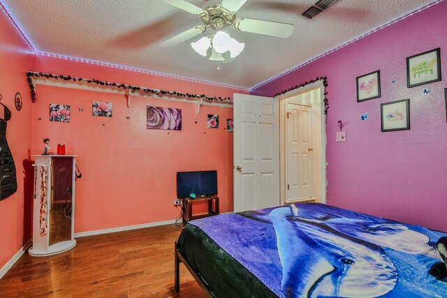 bedroom featuring ceiling fan, wood-type flooring, and a textured ceiling