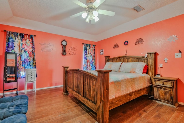 bedroom featuring ceiling fan, hardwood / wood-style floors, and a textured ceiling