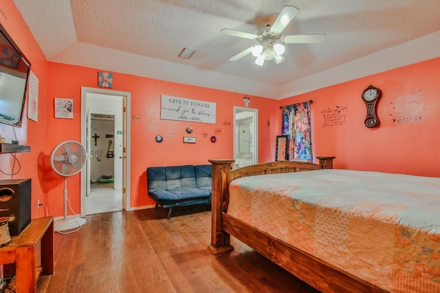 bedroom featuring ceiling fan, light hardwood / wood-style floors, a textured ceiling, and ensuite bathroom