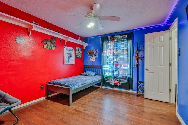 bedroom featuring ceiling fan, hardwood / wood-style flooring, and a textured ceiling