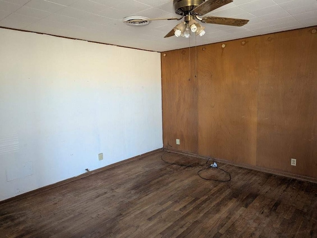 unfurnished room with hardwood / wood-style flooring, ceiling fan, and wooden walls