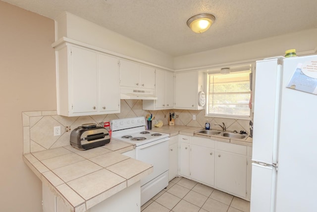 kitchen with white cabinetry, sink, tile countertops, and white appliances