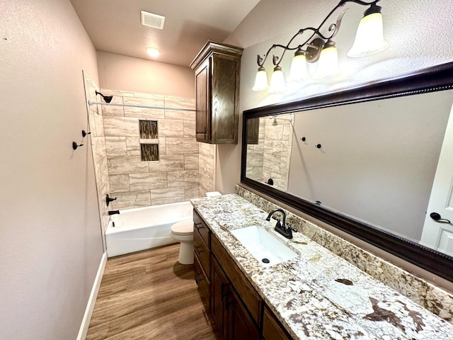 full bathroom with vanity, hardwood / wood-style flooring, toilet, and tiled shower / bath combo