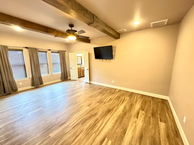 spare room featuring beamed ceiling, wood-type flooring, and ceiling fan