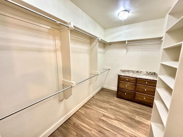 walk in closet with light hardwood / wood-style flooring