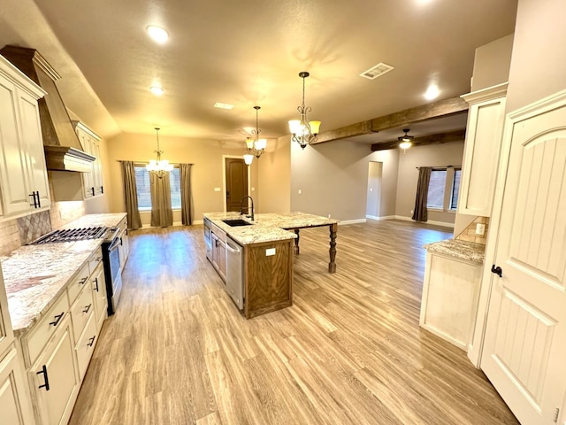 kitchen with hanging light fixtures, an island with sink, and light stone countertops