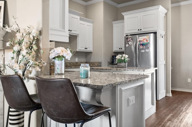 kitchen featuring stone countertops, stainless steel fridge, a kitchen breakfast bar, white cabinets, and dark hardwood / wood-style flooring