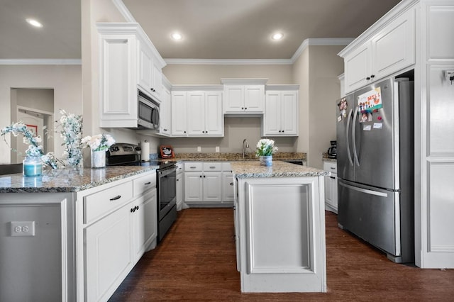 kitchen featuring appliances with stainless steel finishes, white cabinetry, ornamental molding, a center island, and light stone countertops