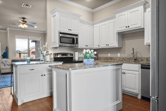 kitchen featuring a kitchen island, white cabinetry, appliances with stainless steel finishes, and dark wood-type flooring