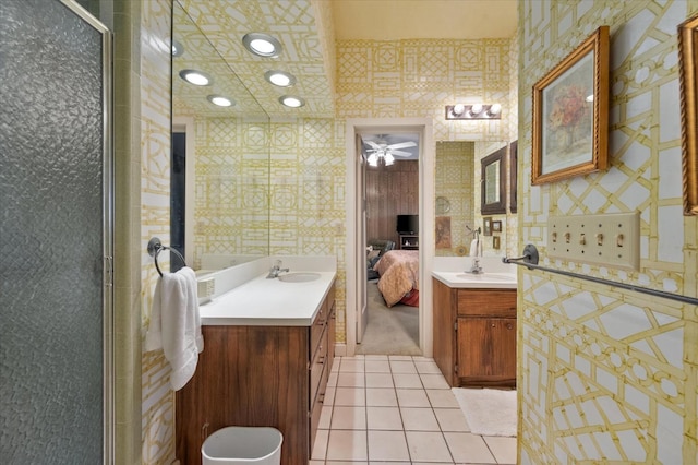 bathroom featuring connected bathroom, a shower stall, wallpapered walls, two vanities, and tile patterned floors