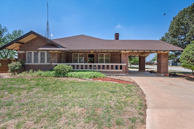 ranch-style house with brick siding, a shingled roof, a front lawn, concrete driveway, and a chimney