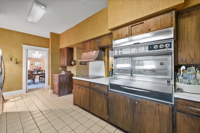 kitchen with light tile patterned floors, oven, light countertops, under cabinet range hood, and black electric stovetop
