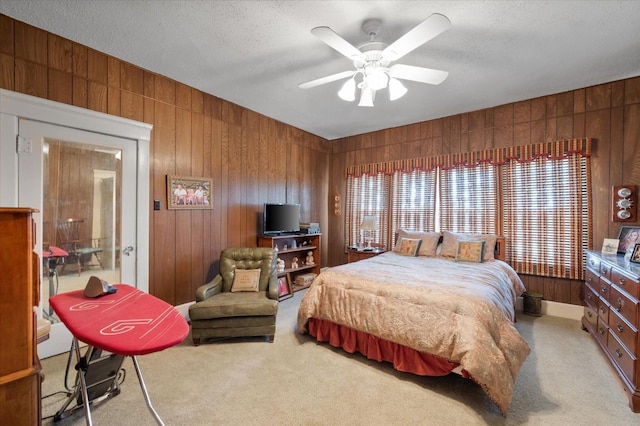 carpeted bedroom featuring ceiling fan, wood walls, and a textured ceiling