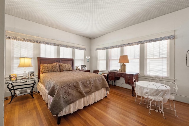 bedroom with multiple windows and wood finished floors