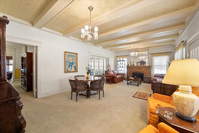 interior space with light carpet, beam ceiling, a fireplace, baseboards, and a chandelier