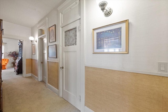 hallway with baseboards and light carpet