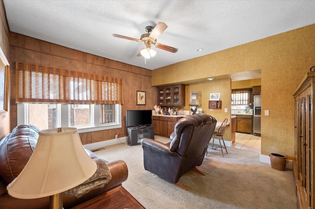 living room featuring light colored carpet, a textured ceiling, and a ceiling fan