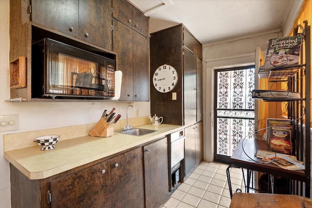 kitchen with light tile patterned floors, a sink, light countertops, dark brown cabinetry, and black microwave