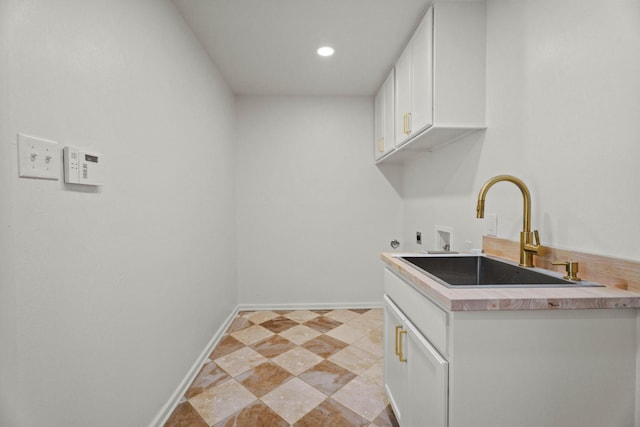 laundry room with a sink, electric dryer hookup, cabinet space, baseboards, and washer hookup