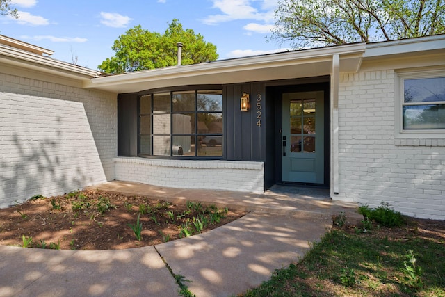 doorway to property featuring brick siding and board and batten siding