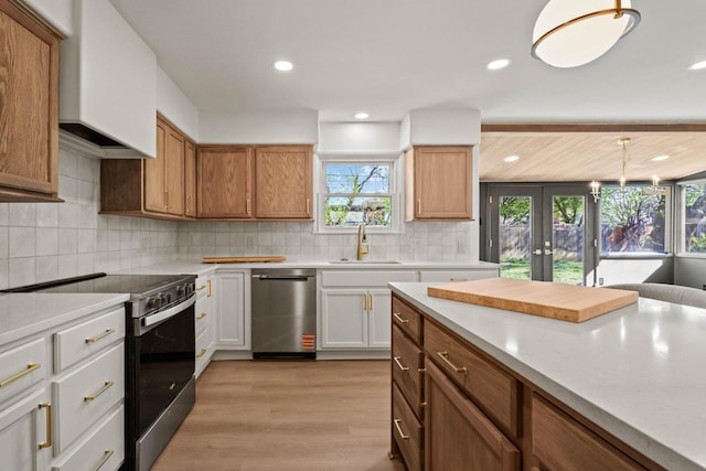 kitchen featuring light countertops, french doors, a sink, light wood-style floors, and appliances with stainless steel finishes