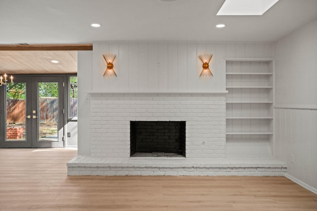 unfurnished living room with built in features, a brick fireplace, wood finished floors, and recessed lighting