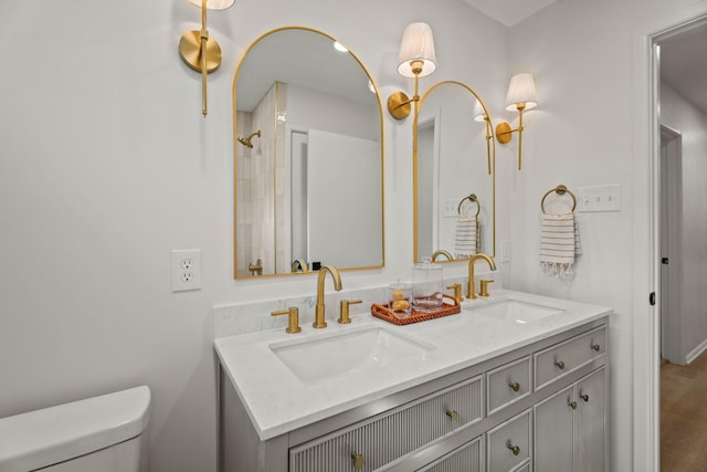 full bathroom with toilet, a sink, and double vanity