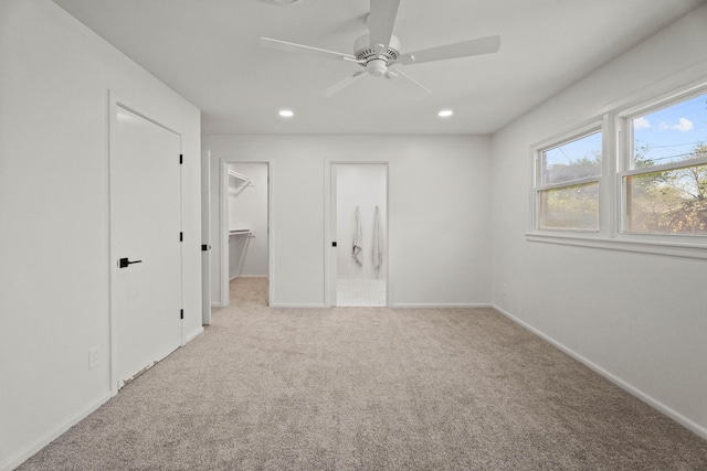 unfurnished bedroom featuring a walk in closet, carpet flooring, baseboards, and recessed lighting