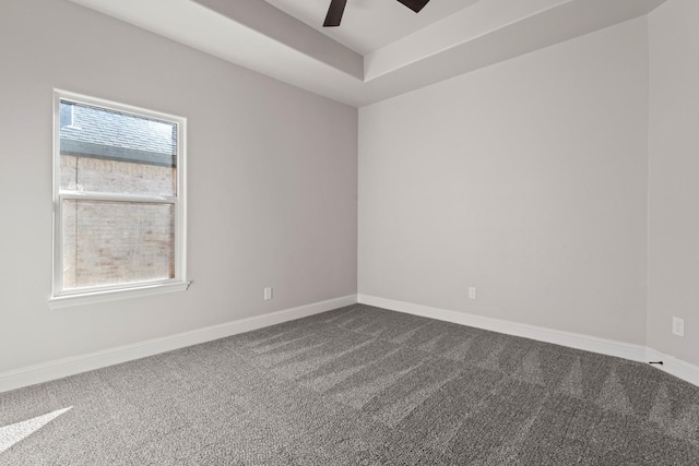 carpeted empty room featuring ceiling fan and a raised ceiling