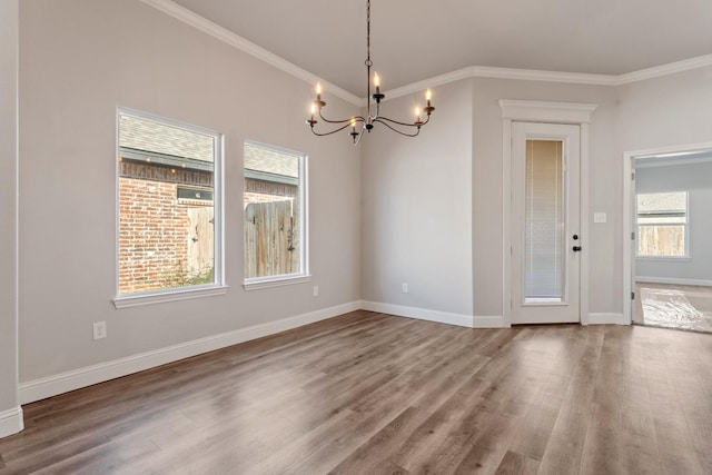 unfurnished dining area with an inviting chandelier, ornamental molding, and hardwood / wood-style floors