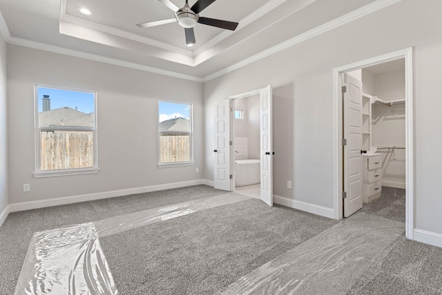 unfurnished bedroom with ornamental molding, a spacious closet, and a raised ceiling