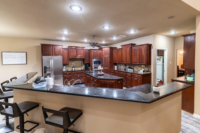 kitchen with stainless steel appliances, a sink, a large island, decorative backsplash, and ceiling fan