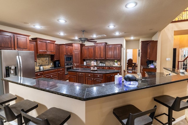 kitchen with stainless steel appliances, a kitchen breakfast bar, recessed lighting, backsplash, and ceiling fan