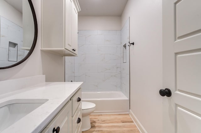 full bathroom with hardwood / wood-style flooring, vanity, tiled shower / bath, and toilet