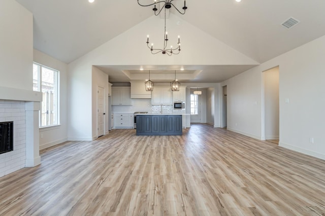 kitchen with pendant lighting, a raised ceiling, light hardwood / wood-style floors, and a brick fireplace