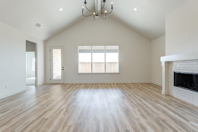 unfurnished living room featuring high vaulted ceiling, light wood-type flooring, a chandelier, and a fireplace