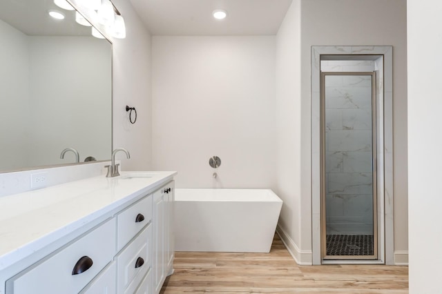 bathroom with vanity, wood-type flooring, and plus walk in shower