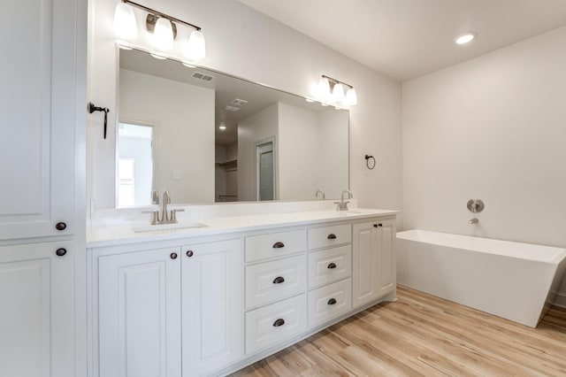 bathroom with vanity, a tub to relax in, and hardwood / wood-style flooring