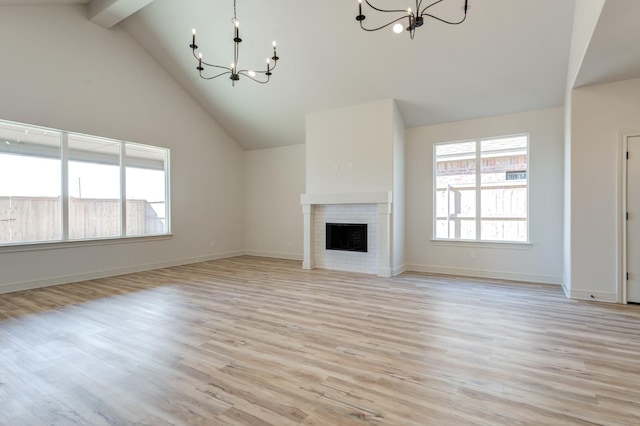 unfurnished living room with a brick fireplace, light hardwood / wood-style floors, and a chandelier