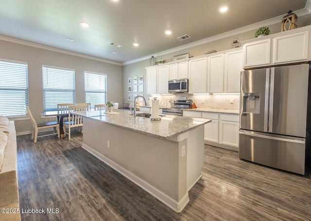 3301 Venita Ave, Lubbock, TX 79407 - kitchen featuring appliances with stainless steel finishes, ornamental molding, dark wood-style floors, white cabinetry, and an island with sink