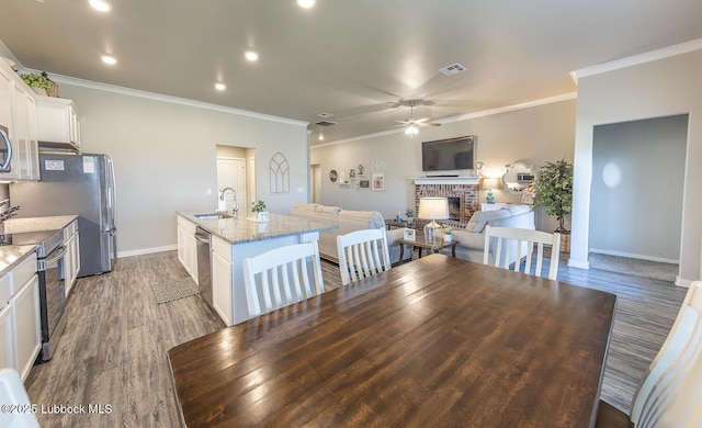 3301 Venita Ave, Lubbock, TX 79407 - dining room with a ceiling fan, a fireplace, crown molding, light wood-style floors, and recessed lighting