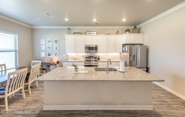 3301 Venita Ave, Lubbock, TX 79407 - kitchen featuring appliances with stainless steel finishes, a center island with sink, white cabinetry, crown molding, and tasteful backsplash